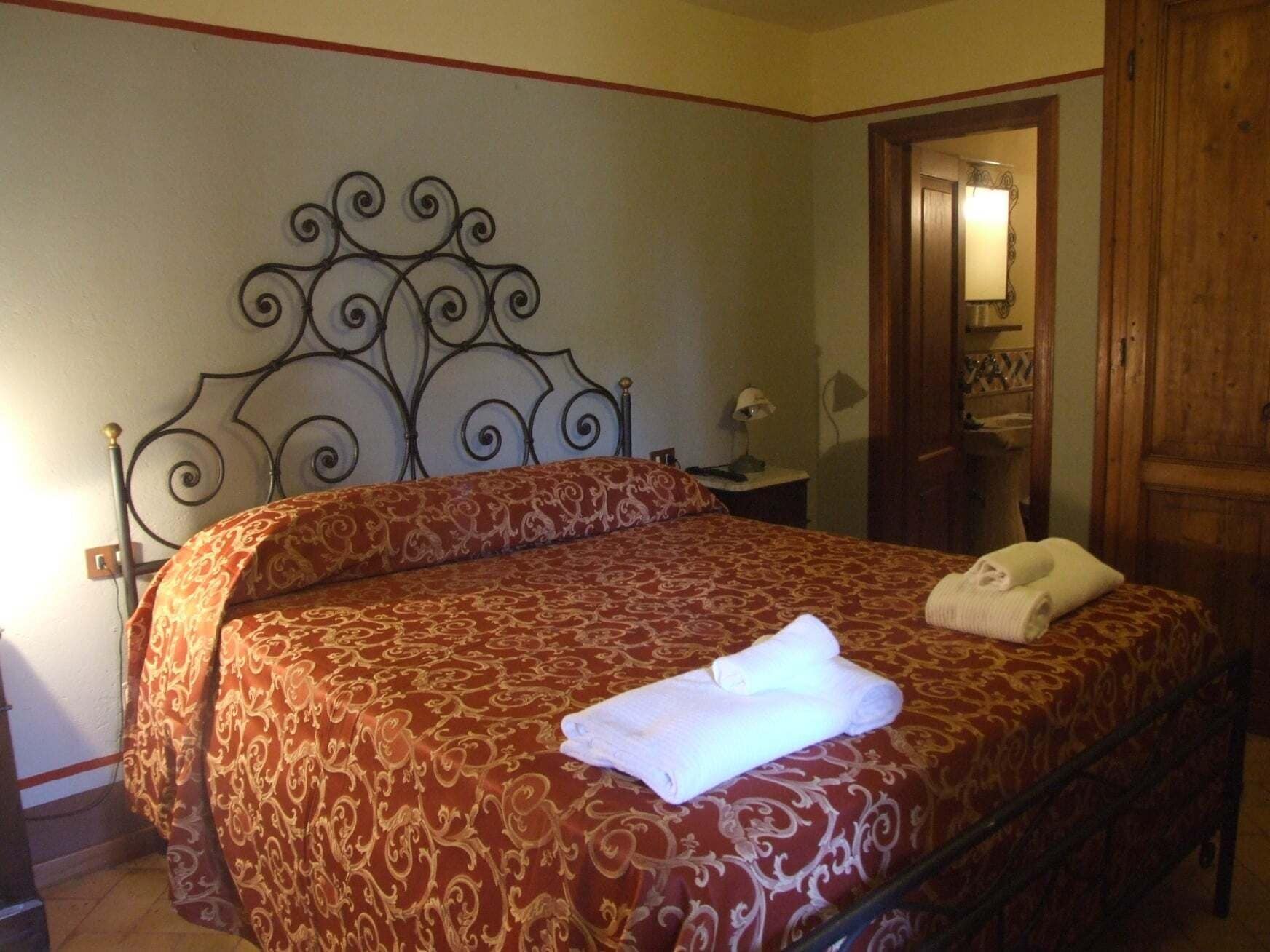Un lit bien fait, avec une couvre-lit à motifs et une serviette pliée posée dessus.