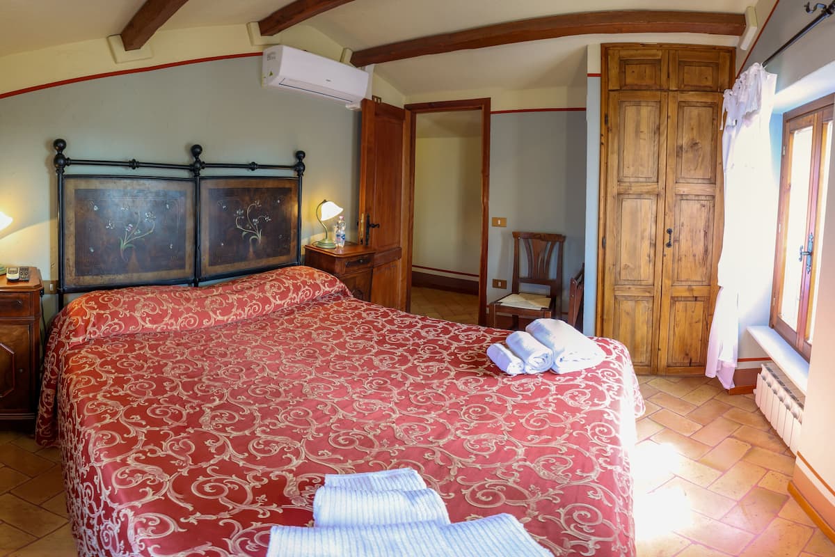 Ein Schlafzimmer mit einem großen Bett, einem Holzkopfende, zwei Nachttischen mit Lampen, einem Schrank aus Holz und einem Spiegel.