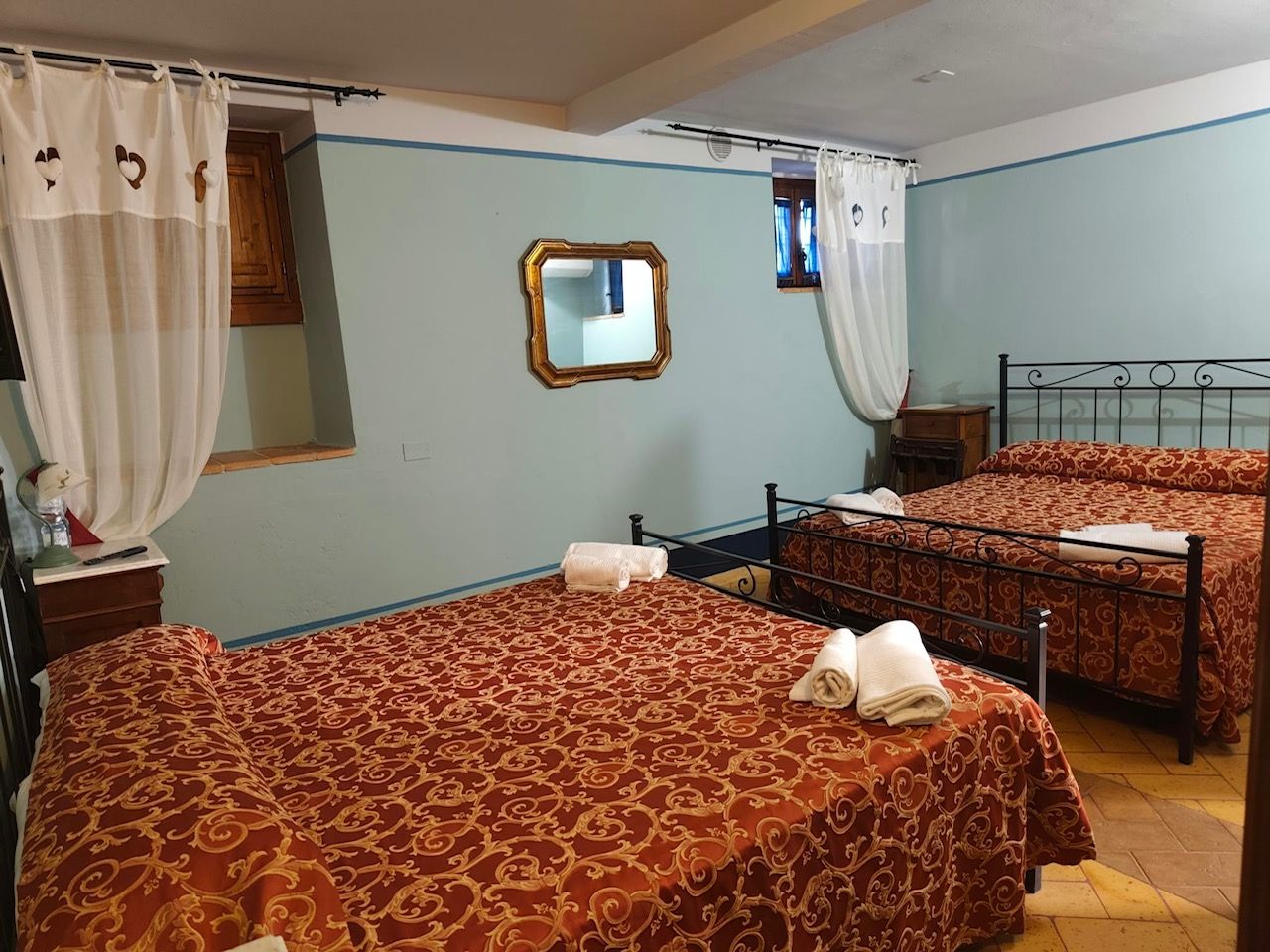 Habitación de hotel con dos camas, un espejo y un ventanal con cortinas.