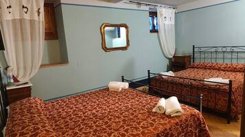 A hotel room with two beds, a mirror, and a window with curtains.