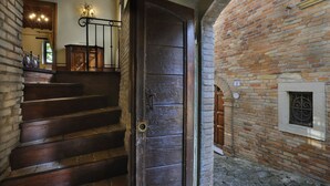 A wooden staircase leading to a room with a brick wall and a window with a decorative grille. - Albergo Diffuso Borgo Montemaggiore (Colli al Metauro)