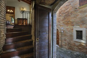 Una escalera de madera que conduce a una habitación con pared de ladrillo y una ventana con celosía decorativa.