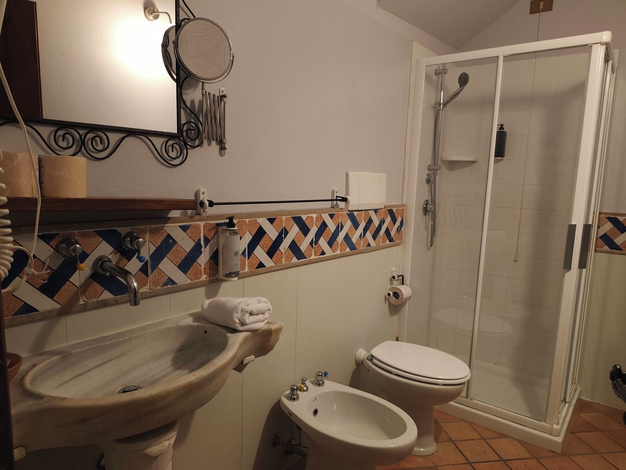 Casa de banho com lavatório, sanita, bidé, chuveiro e espelho.