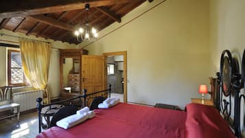 Une chambre à coucher avec un lit en bois, une table de chevet, une lampe, un miroir et une fenêtre avec des rideaux.