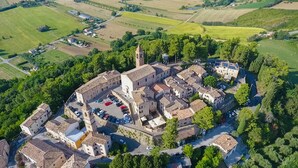 An aerial view of a historic town with a central square, surrounded by buildings and green fields. - Albergo Diffuso Borgo Montemaggiore (Colli al Metauro)