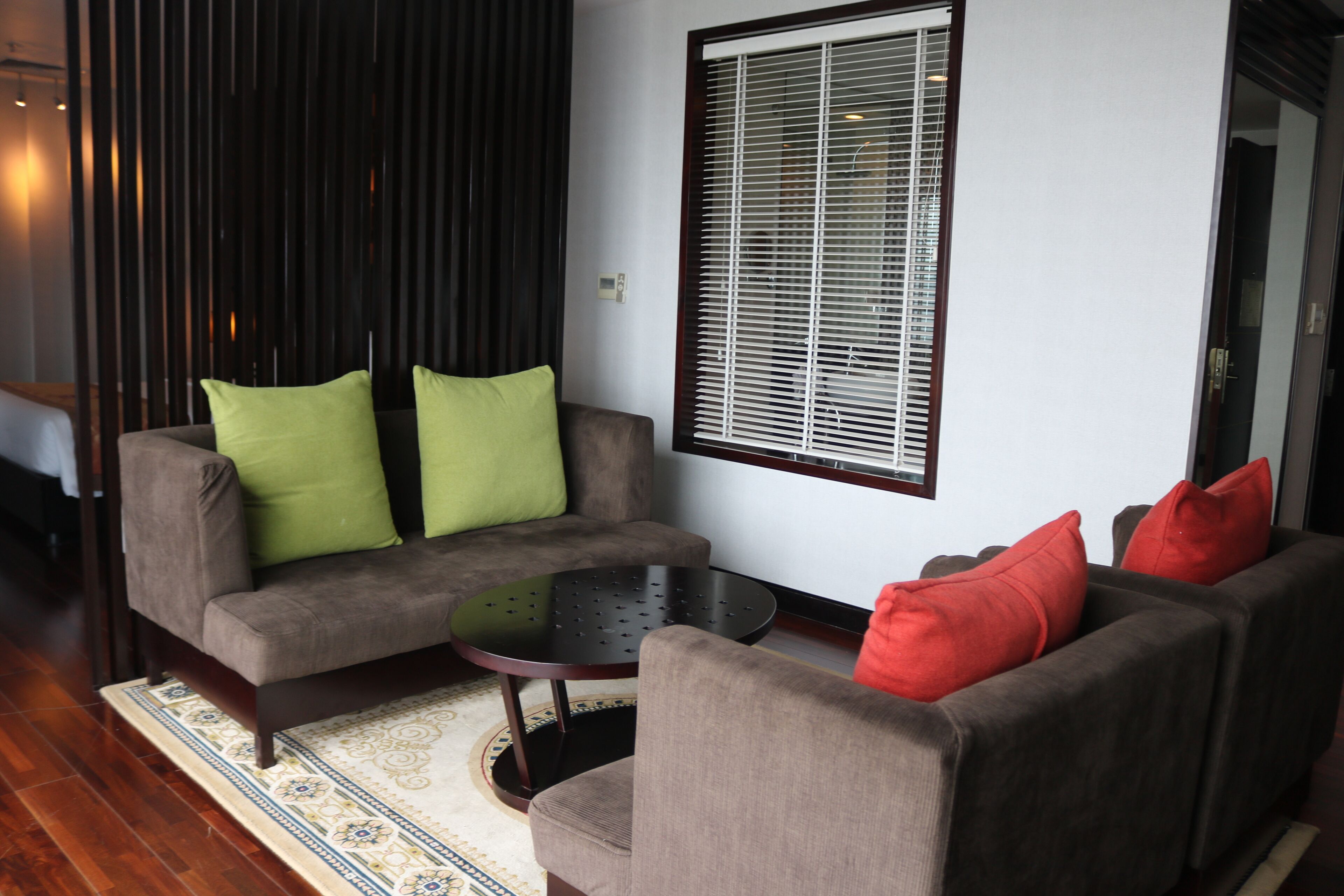 A modern living room with a sofa set, a coffee table, and a window with blinds.
