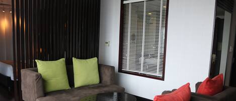 A modern living room with a sofa set, a coffee table, and a window with blinds.