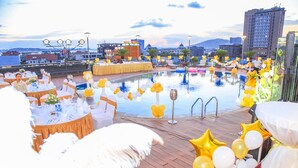 A rooftop pool area with tables set for a formal event, surrounded by yellow and white balloons. - Halong Palace Hotel (Bai Chay)