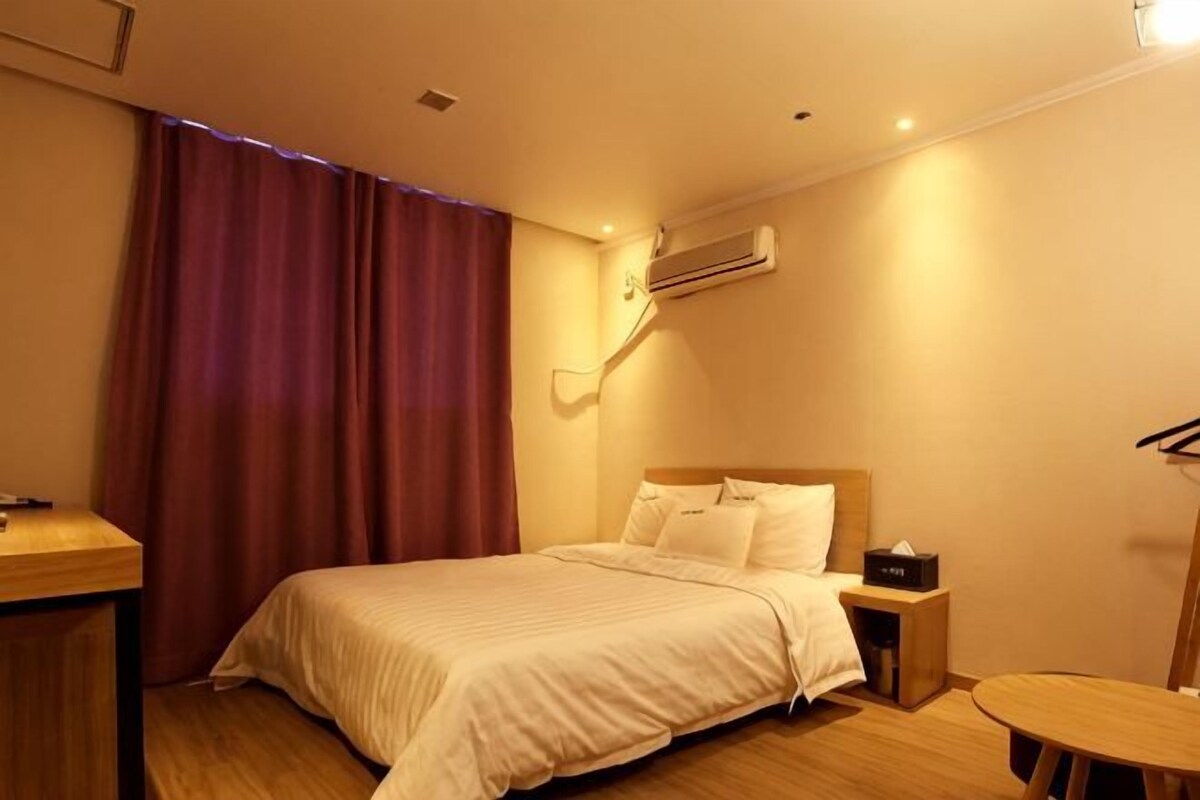 Quarto de hotel com cama, mesa de cabeceira e ar condicionado.