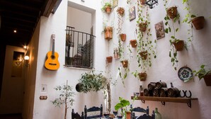 Ein Innenhof mit Terrakottafliesen, einem Holztisch mit Stühlen und Kübelpflanzen an den Wänden.