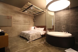 Una habitación de hotel moderna con una cama grande, un baño independiente con bañera separada y una cita motivacional en la pared.