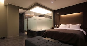 Una habitación de hotel moderna con una cama grande, una zona de estar y un área de ducha con paredes de vidrio.