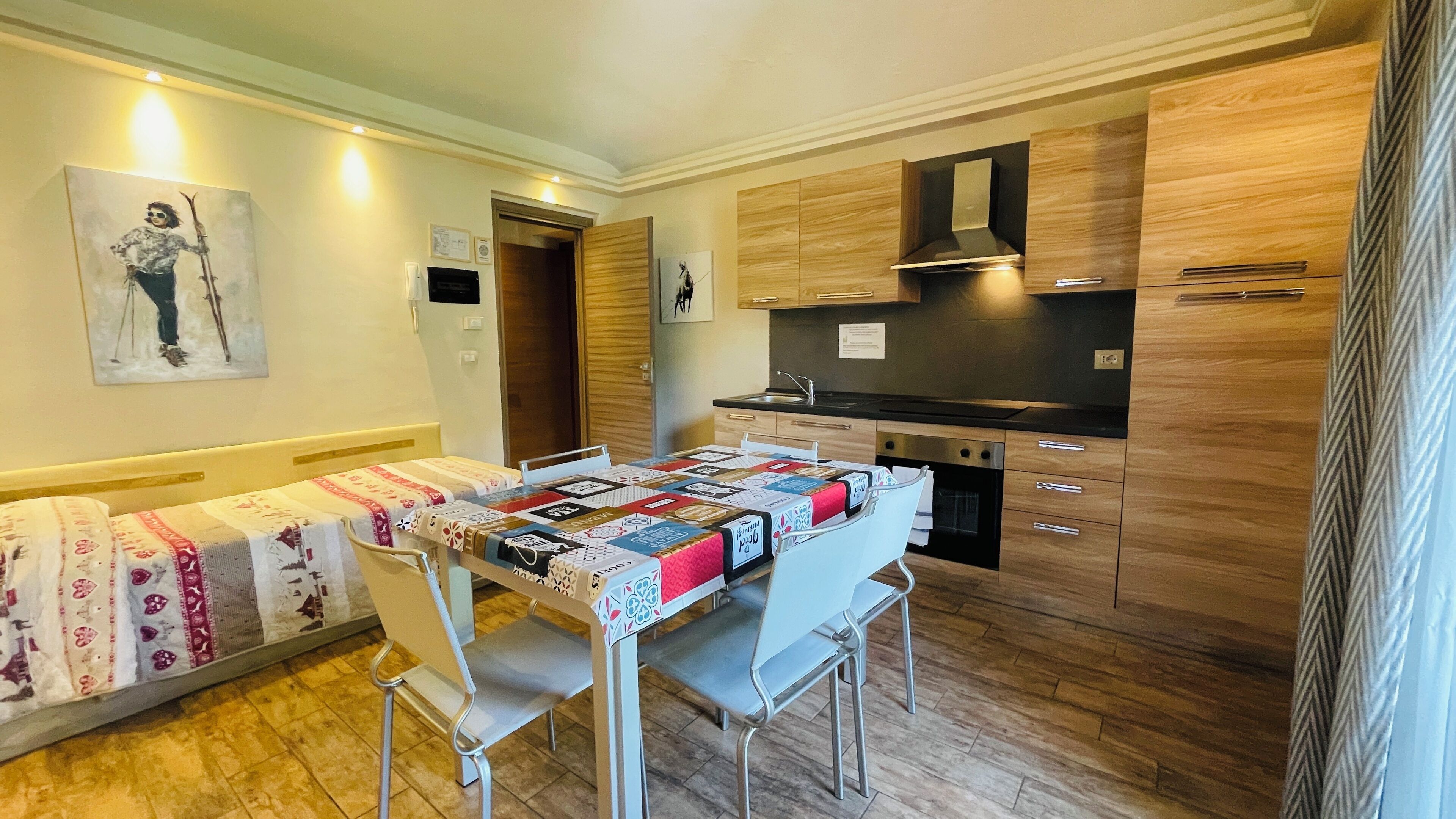 A compact kitchen with wooden cabinets, a built-in oven, and a dining table with chairs.
