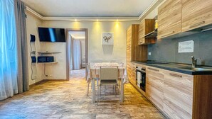 Una cocina moderna con armarios de madera, horno empotrado y televisor de pantalla plana montado en la pared.