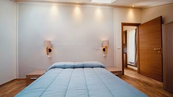 Un dormitorio con una cama, dos lámparas de pared, un armario de madera y un tragaluz.