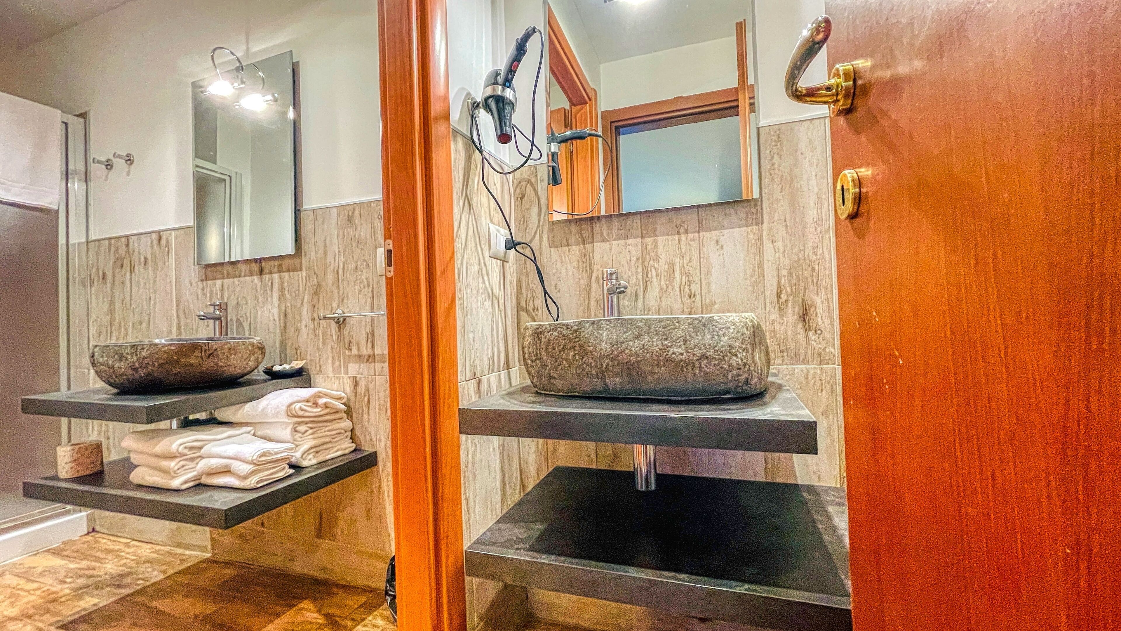 A bathroom with two sinks, one with a bowl and one with a vessel sink, both with towel racks.