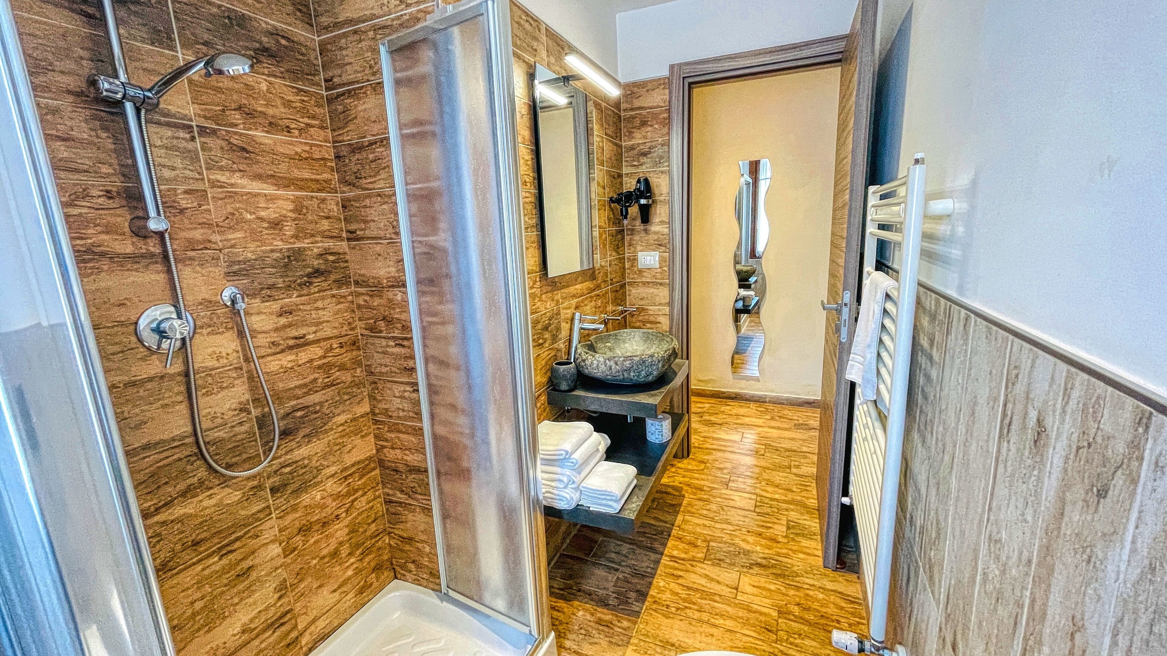 Un baño moderno con ducha, lavabo de gran tamaño y un perchero para toallas.