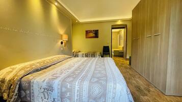 A hotel room with a large bed, a wardrobe, a desk, and a chair.