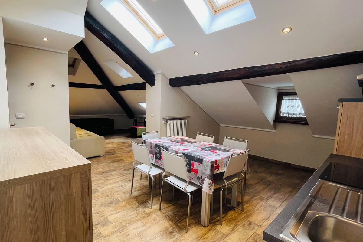 A modern kitchen with a dining area, skylights, and a lofted sleeping area.