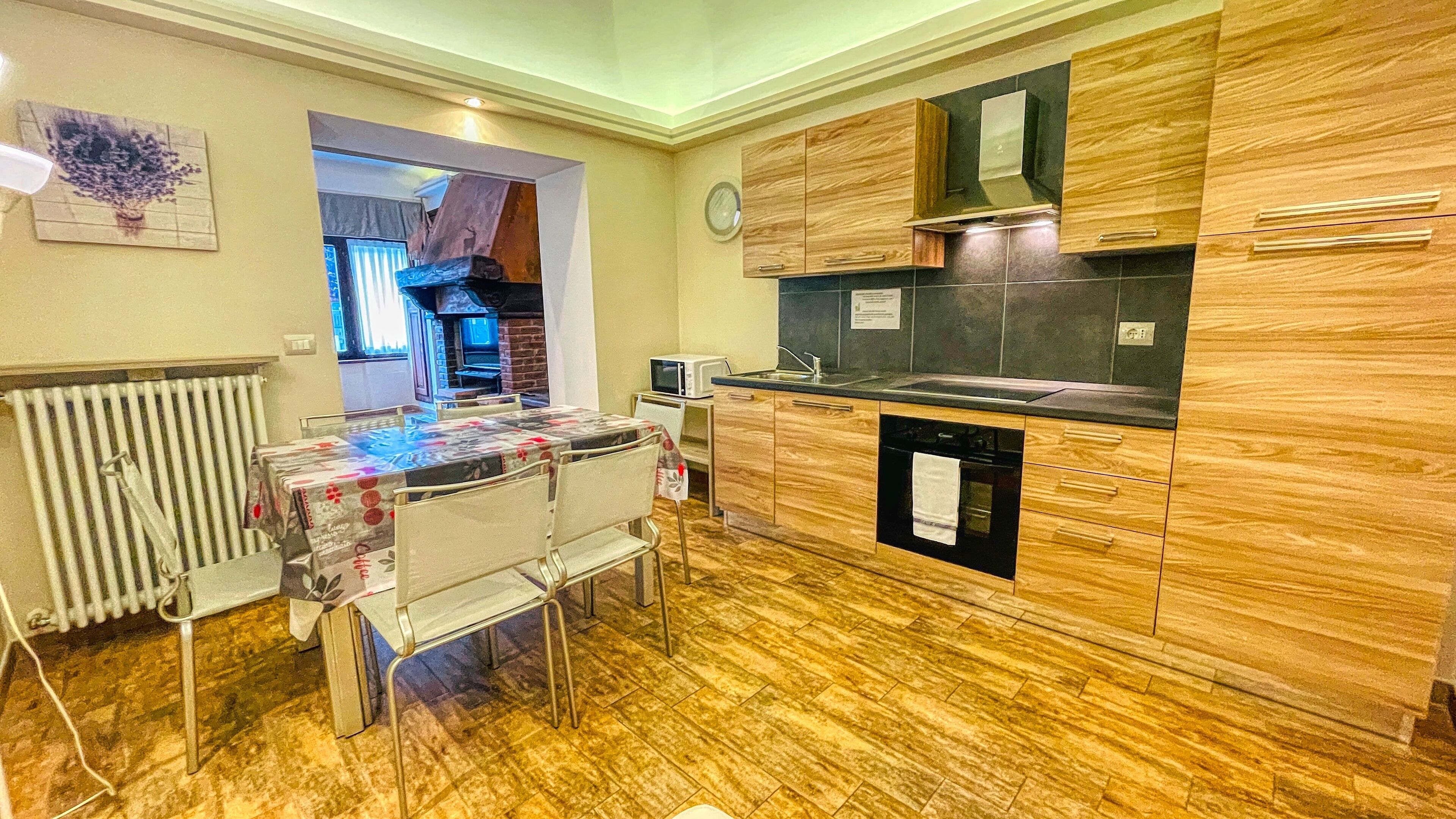 A compact kitchen with wooden cabinets, a built-in oven, and a dining area with a table and chairs.