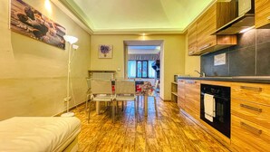 Una cocina compacta con armarios de madera, un comedor con sillas y un radiador visible.