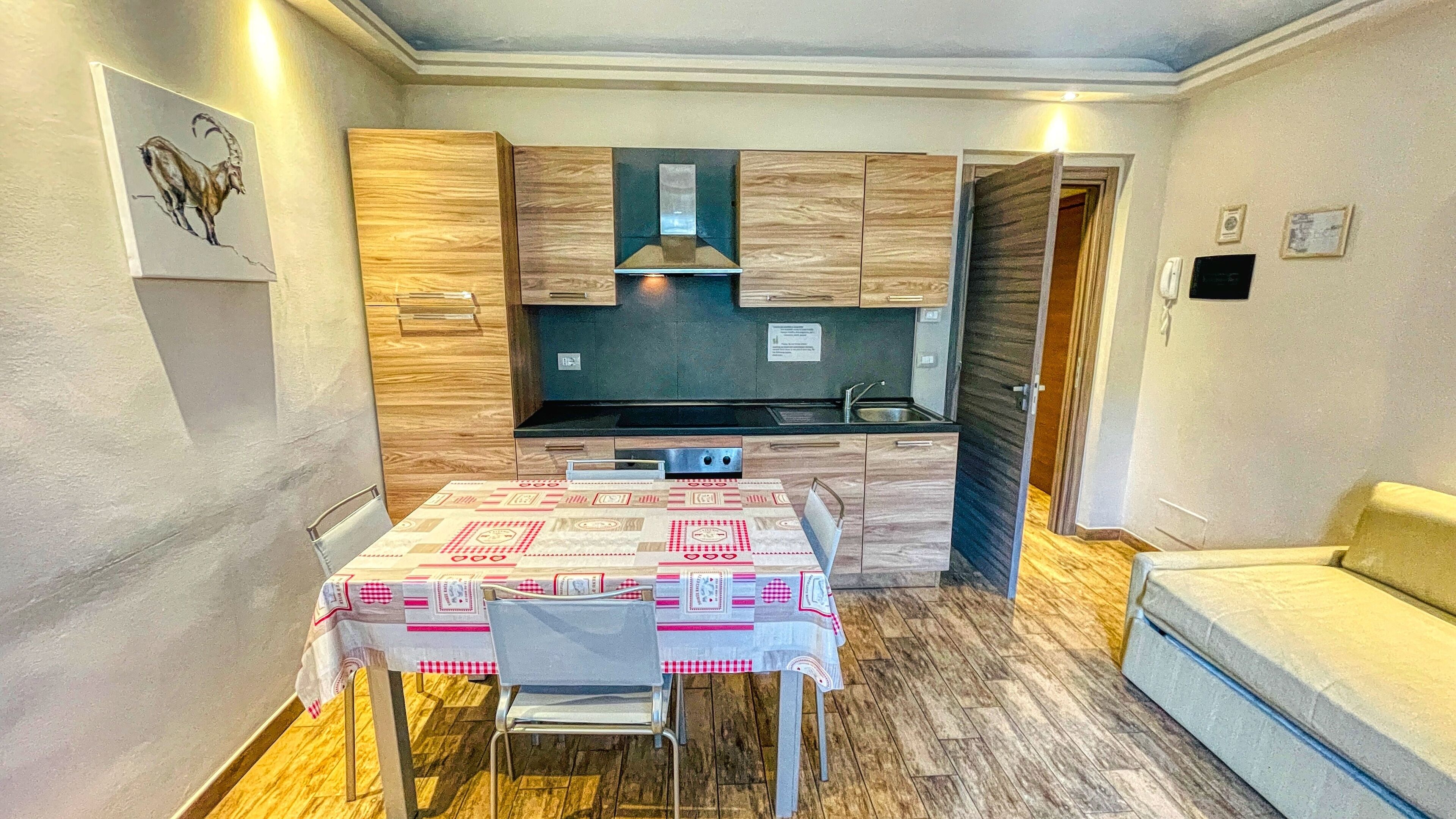 A compact kitchen with wooden cabinets, a built-in stove, and a dining table with chairs.