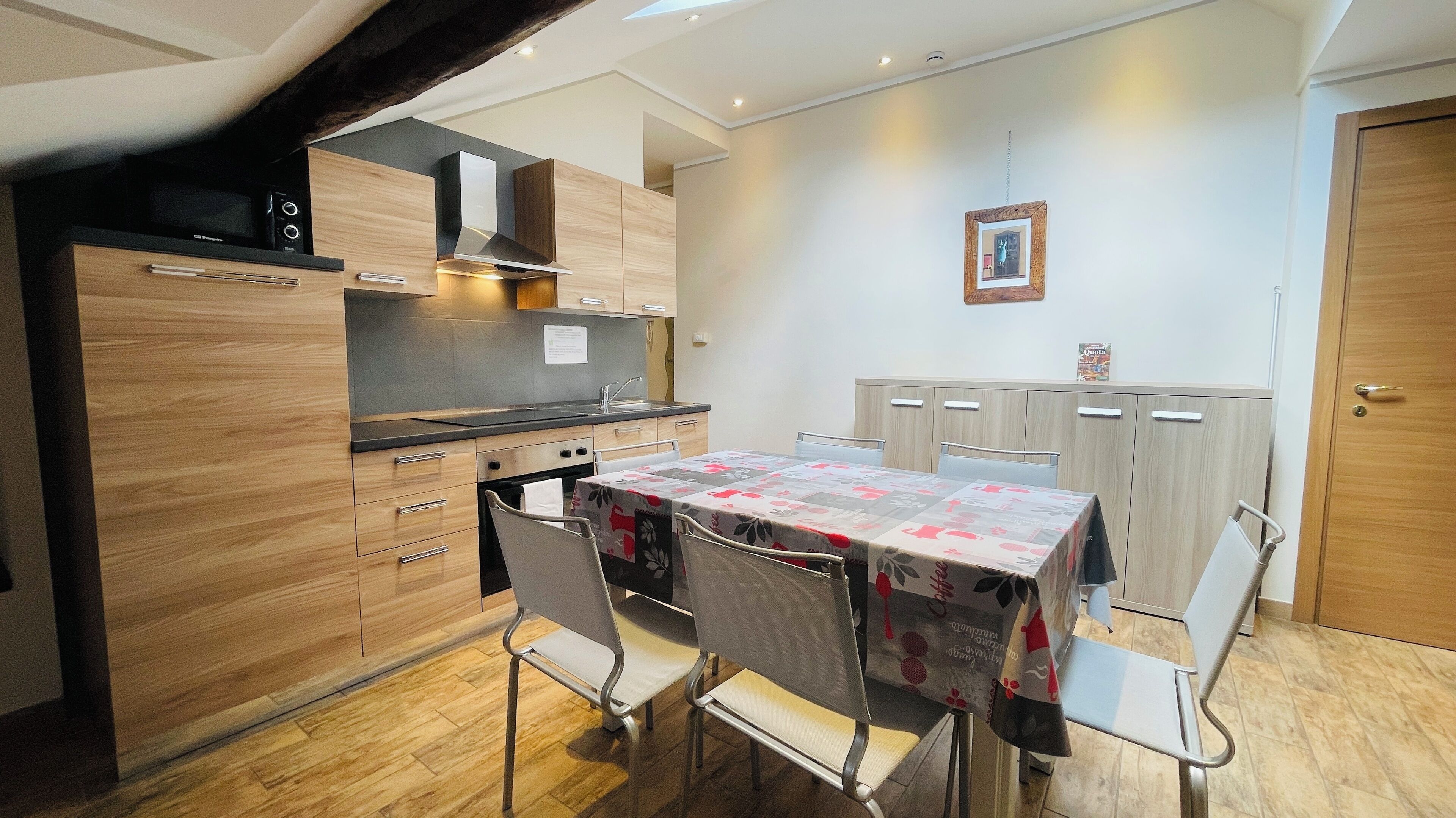 Una cocina compacta con armarios de madera, horno empotrado y una mesa de comedor con sillas.