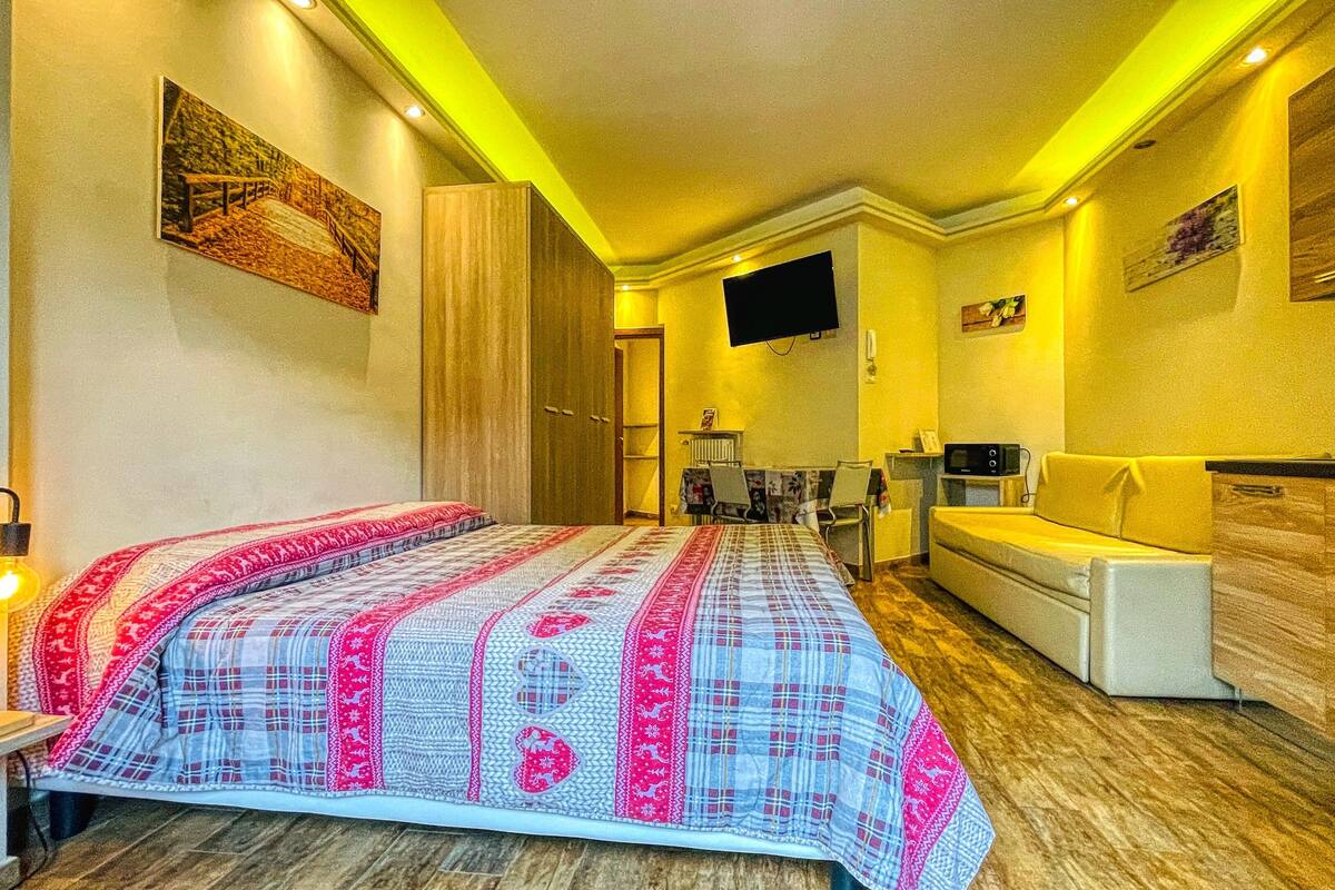 A modern hotel room with a large bed, a sofa, a TV, and a microwave.