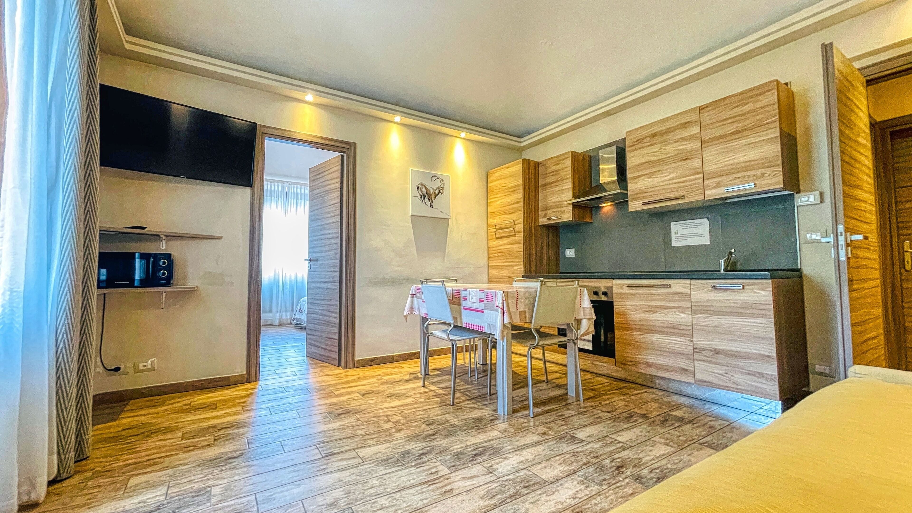 Une cuisine compacte avec des meubles en bois, une table à manger avec des chaises et un petit réfrigérateur.