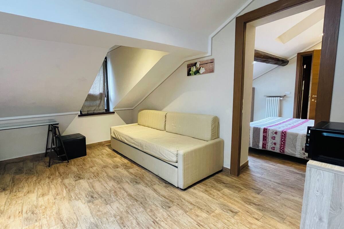 A small, well-lit room with a sofa, a table, and a ladder.