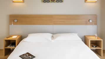 Een netjes opgemaakt bed met witte lakens, twee nachtkastjes met lampen, een kunstwerk aan de muur en een houten hoofdbord.