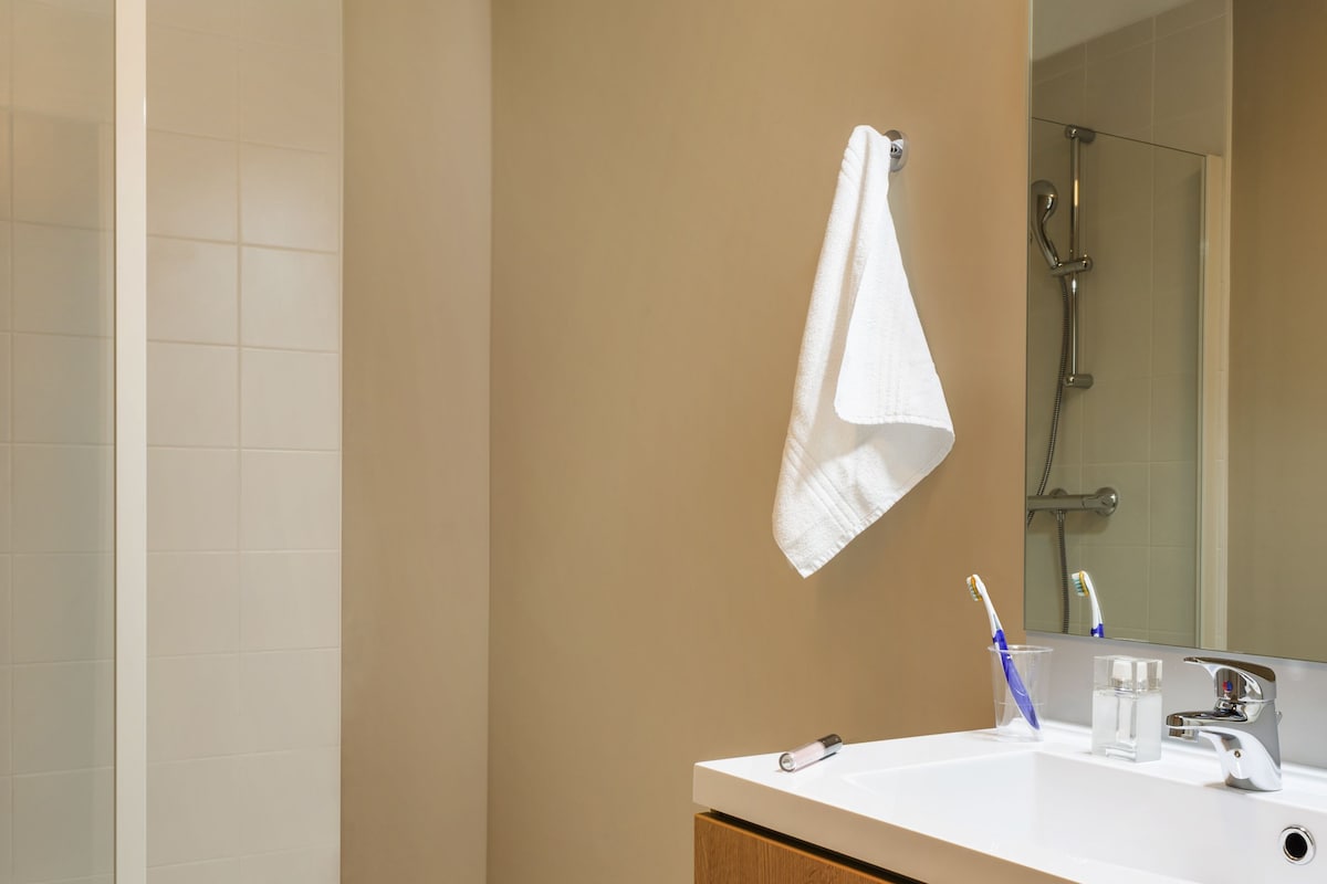 Un baño moderno con ducha, lavabo con espejo y mueble de madera.