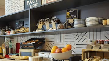 A breakfast bar with jars of spreads, a bowl of fruit, and a coffee machine.