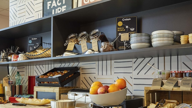 A breakfast bar with jars of spreads, a bowl of fruit, and a coffee machine. - Aparthotel Adagio Access Dijon République (Dijon)