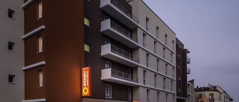 Un hotel de varios pisos con diseño moderno, con balcones y señalización destacada de 'Adagio Apartments'.