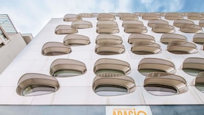 Un edificio moderno con varios ventanales circulares y un cartel que indica 