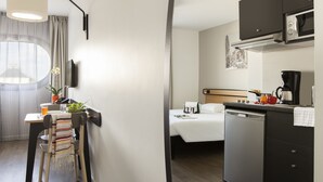 A compact hotel room with a kitchenette, a bed, a dining area with a table and chairs, and a small bathroom. - Aparthotel Adagio Access Nancy Centre (Nancy)