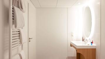 A modern bathroom with a white vanity, a large mirror, and a towel rack with towels.