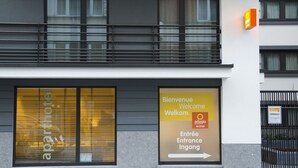 A building with large windows, a sign welcoming visitors, and a sign indicating access to a business or office. - Aparthotel Adagio Access Nancy Centre (Nancy)