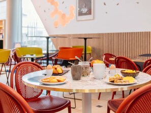A dining area with round tables, red chairs, and a variety of breakfast items. - Aparthotel Adagio Access Nancy Centre (Nancy)