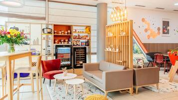 Ein modernes Interieur mit Sofa, Sesseln, einem Couchtisch, einem mit Getränken gefüllten Kühlschrank und einem Wandregal mit Dekoration.