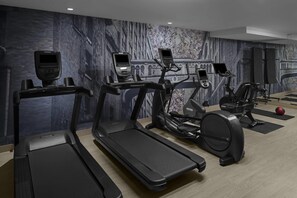 Un gimnasio con cintas de correr, elípticas y una bicicleta estática.