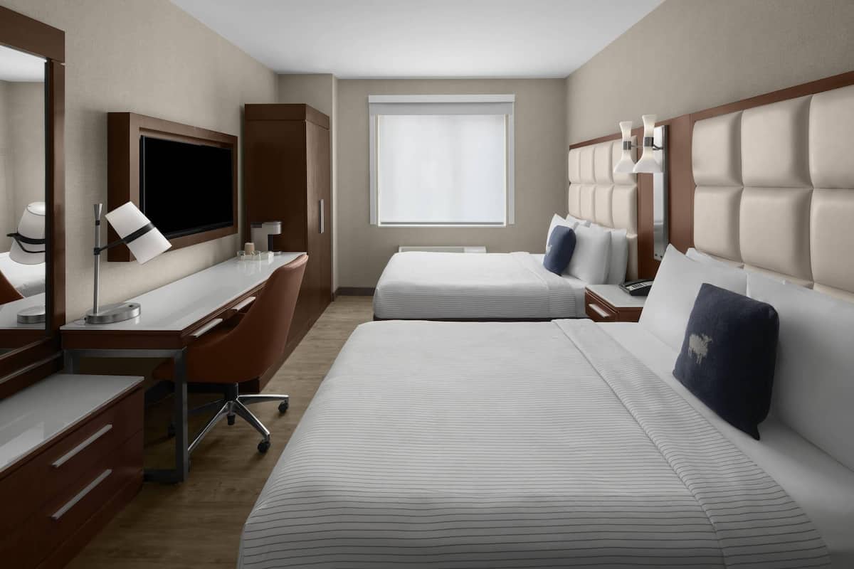 Una habitación de hotel con una cama grande, un escritorio con una silla, un televisor y una ventana.