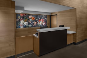 A reception desk with a floral artwork above it, wooden paneling on the walls, and a modern design.