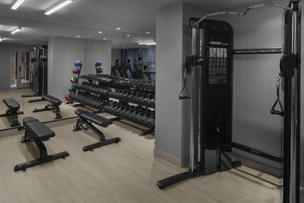 A modern gym with weightlifting equipment, treadmills, and a mirrored wall.