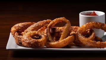 A plate of onion rings with a side of ketchup.