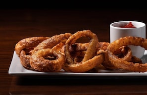 A plate of onion rings with a side of ketchup.