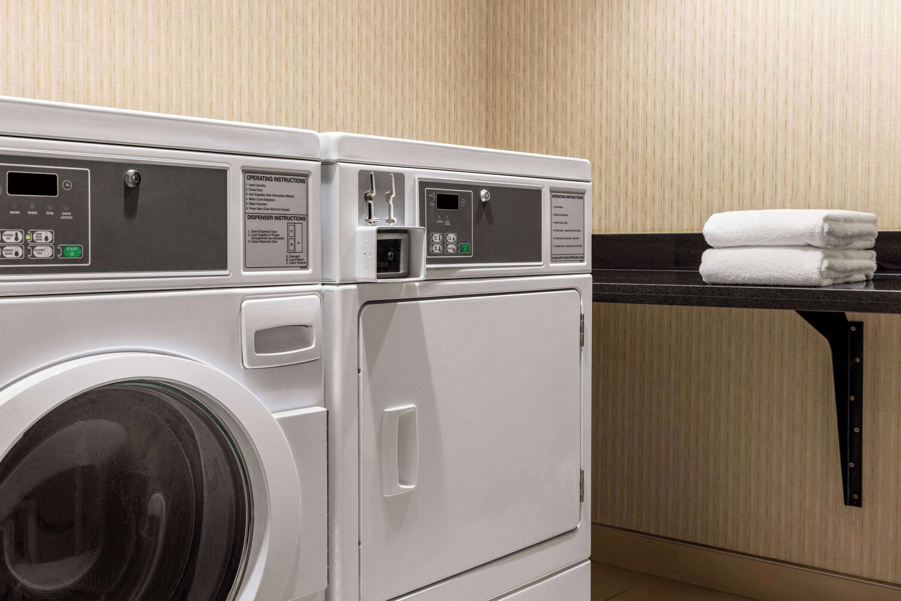 A front-loading washing machine with control panels and operating instructions.