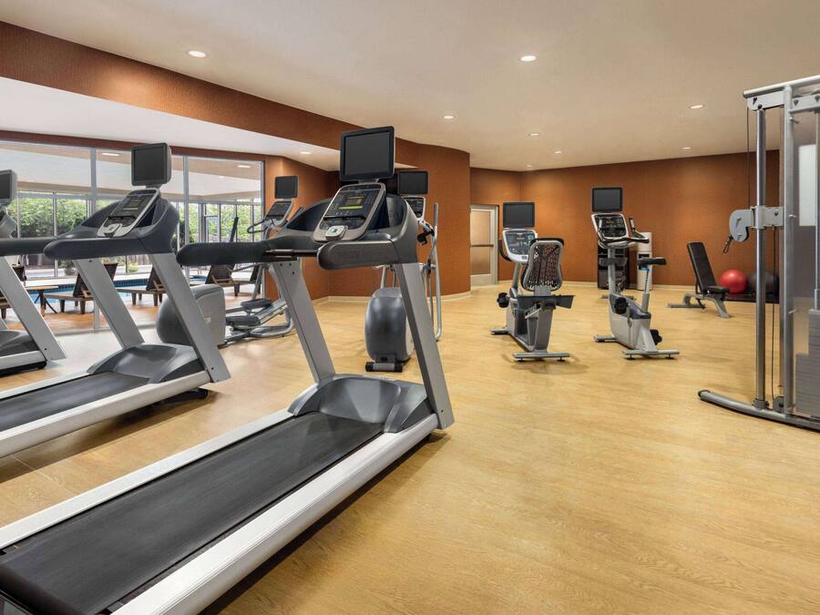 A gym with treadmills, elliptical machines, and exercise balls.