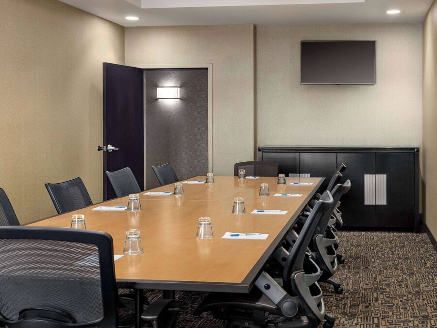 A conference room with a long table, chairs, a TV, and a door.